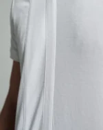 Side view of the white T-shirt showcasing the clean lines and strip body detail running down from the shoulder, emphasizing the minimalistic design and structured fit of the garment.