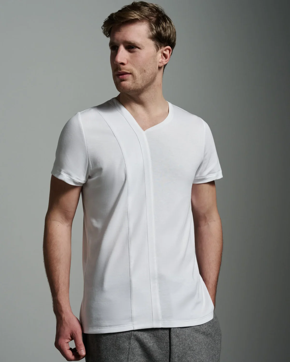 ull front view of the model wearing the white T-shirt, showcasing the asymmetric strip panel and crew neck design, crafted for a sleek and polished appearance, perfect for both casual and refined settings.